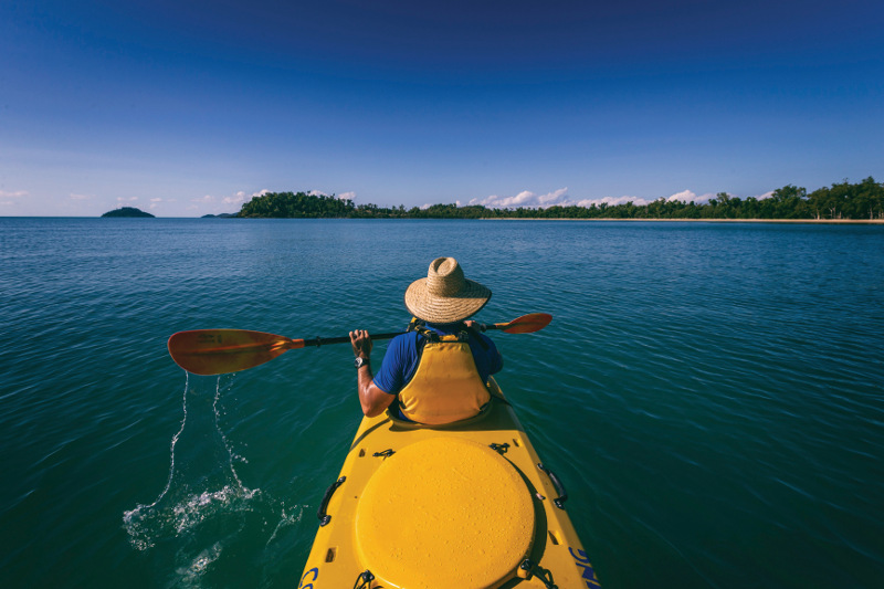 Man in a sea kayak paddles on water near Cairns