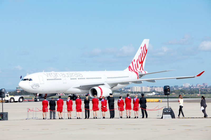 Virgin Australia crew wait on the tarmac in front of a Virgin Australia plane.