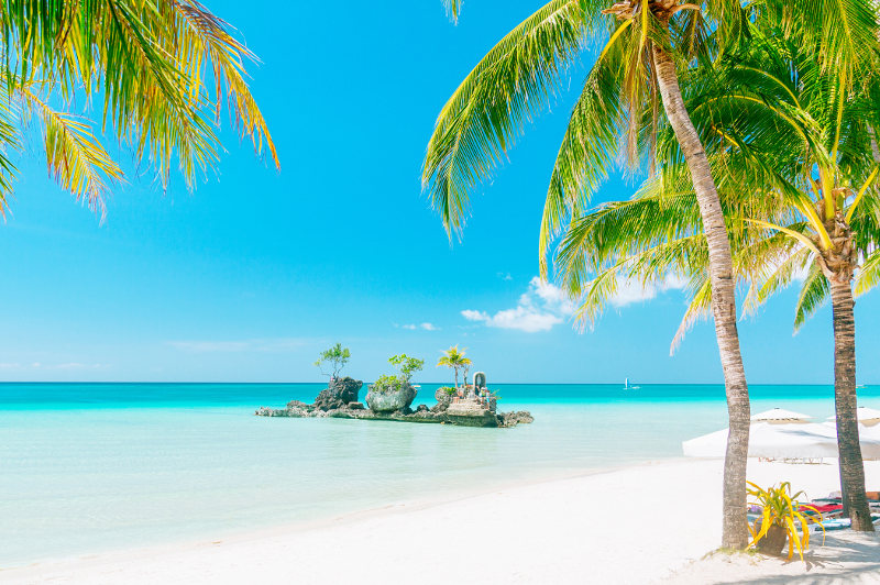 An idyllic scene of palm trees, white sand and aqua waters at Boracay's White Beach in the Philippines.