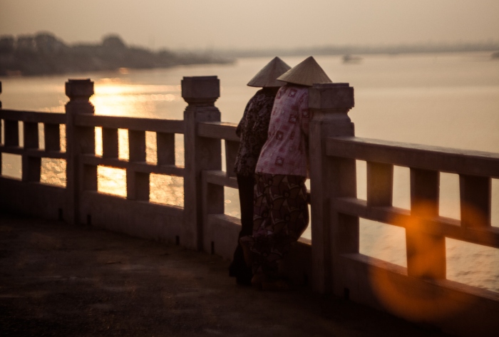 Two women peer over the edge of a bridge over the Red River, Vietnam - cruise trends to try