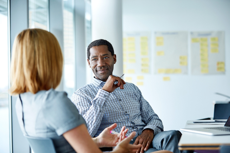 A professional man and woman speaking to one another in a meeting