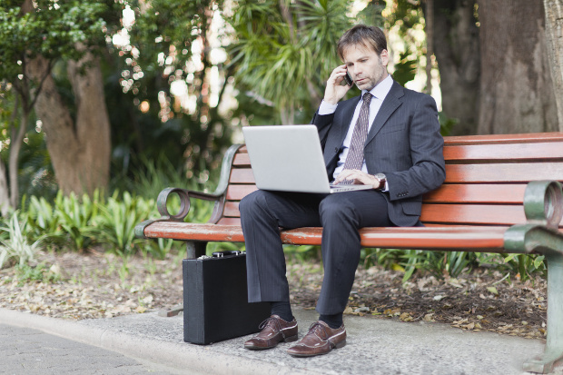 A business man working on a park bench