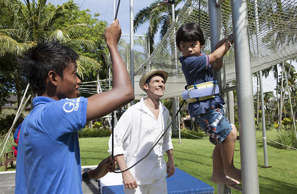 A G.O teaches a young boy how to trapeze