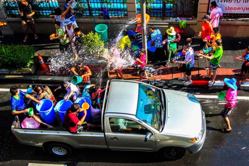 People shooting water pistols at a passing ute filled with people tossing water in bucket, as part of the Songkran festivities in Thailand.