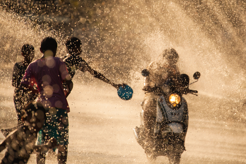 Kids throwing water on a motorcyclist as part of Songkran - the Thai New Year festivities.