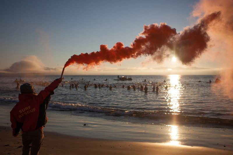 People swimming in the ocean at sunrise in Hobart in the last hours of Dark Mofo festival.