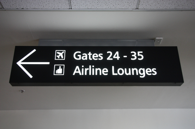 An airport sign pointing to the lounges and gates