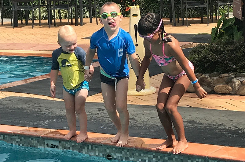 Three children jump into a pool in Fiji