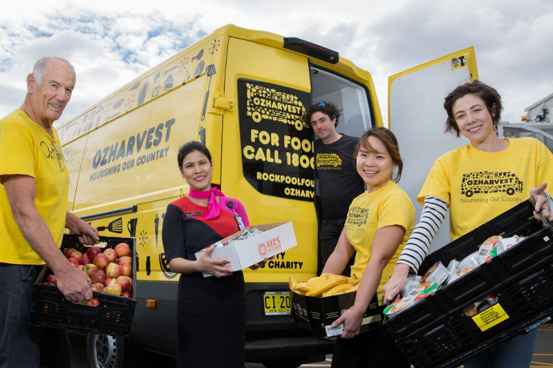 OzHarvest volunteers and a Qantas staffer deliver food from a food rescue van.