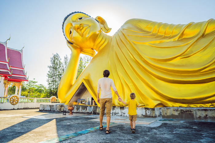father and son admire large buddha in Thailand