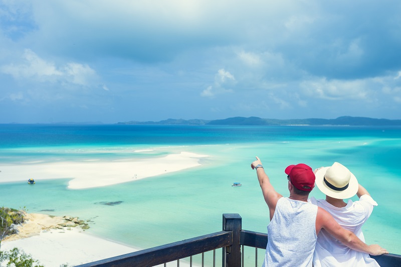 Couple looking at the view of Whitehaven beach. Whitehaven beach is in the Whitsunday islands in Queensland, Australia. 