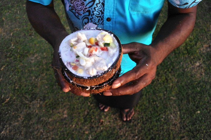 fijian man holding fish salad in coconut