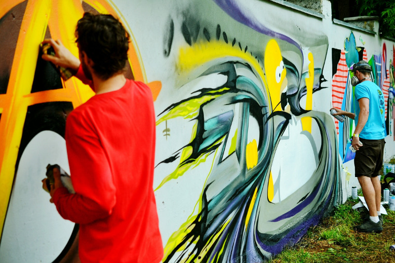 Two men create a graffiti wall mural