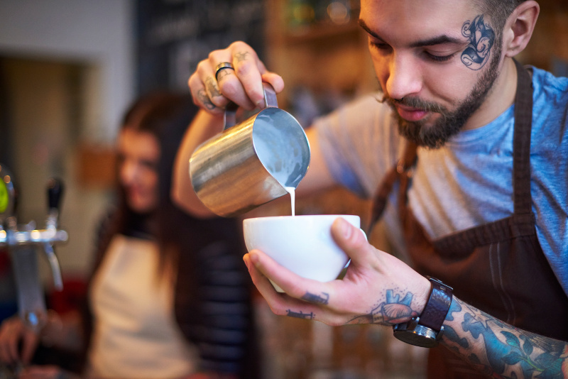 Tattooed barista pours a coffee