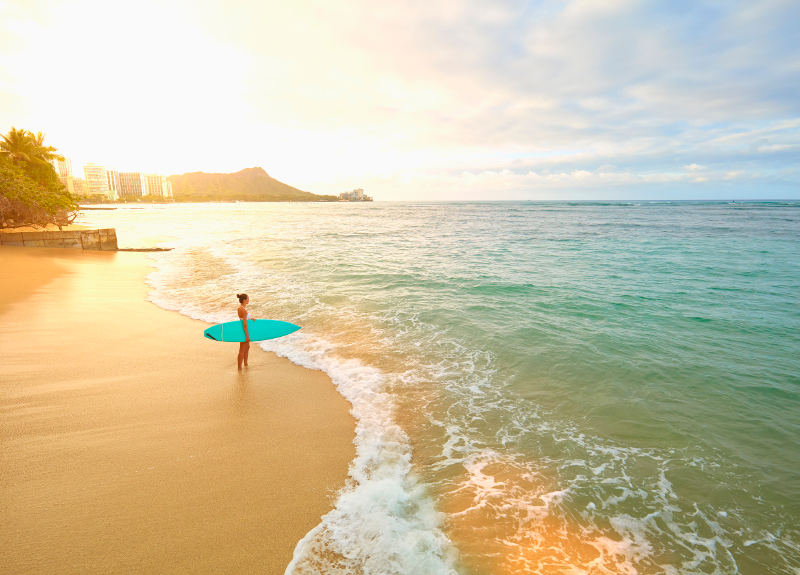 girl on beach with surfboard hawaii