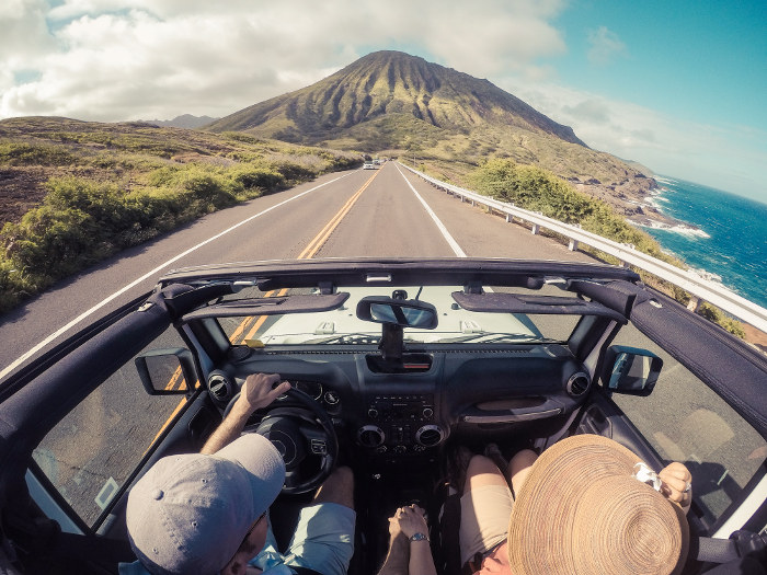 couple in open top car driving maui coastline hawaii