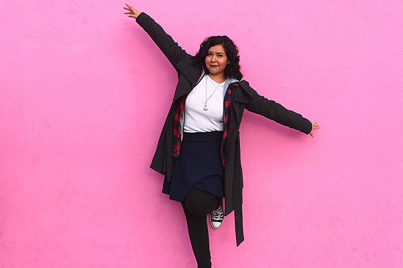 A young woman poses in front of the pink wall on Los Angeles' Melrose Avenue