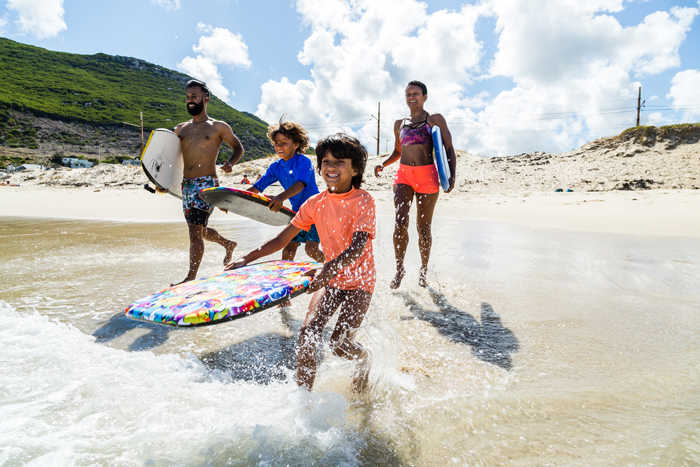 family running into surf - life lessons from travelling with kids