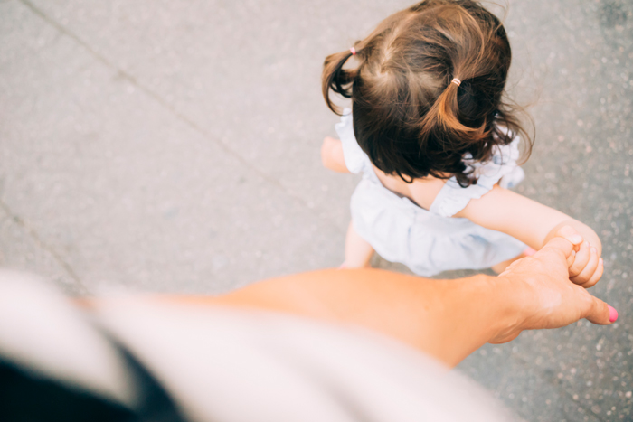 woman holding her toddlers hand while walking - life lessons from travelling with kids