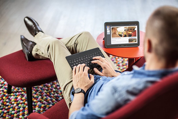 A man using the Logitec keyboard while sitting in a chair