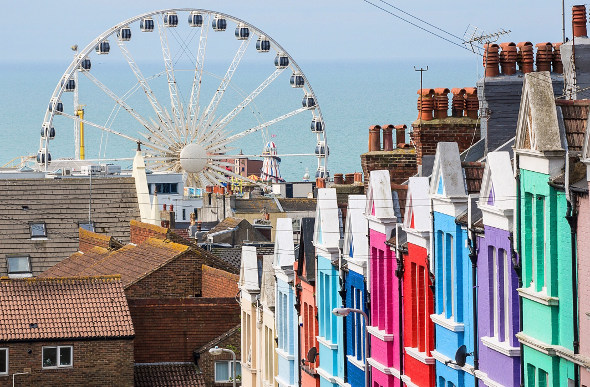 Colourful buildings in Brighton, England, with a ferris wheel and the sea in the background.