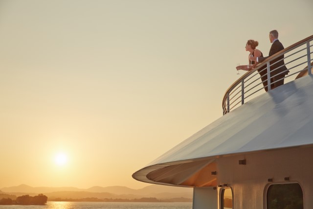 Couple standing on deck of luxury cruise in black tie