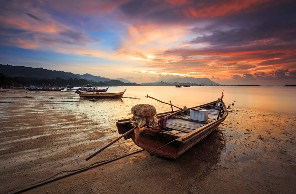 sunset in Langkawi Malaysia with fishing boats on beach