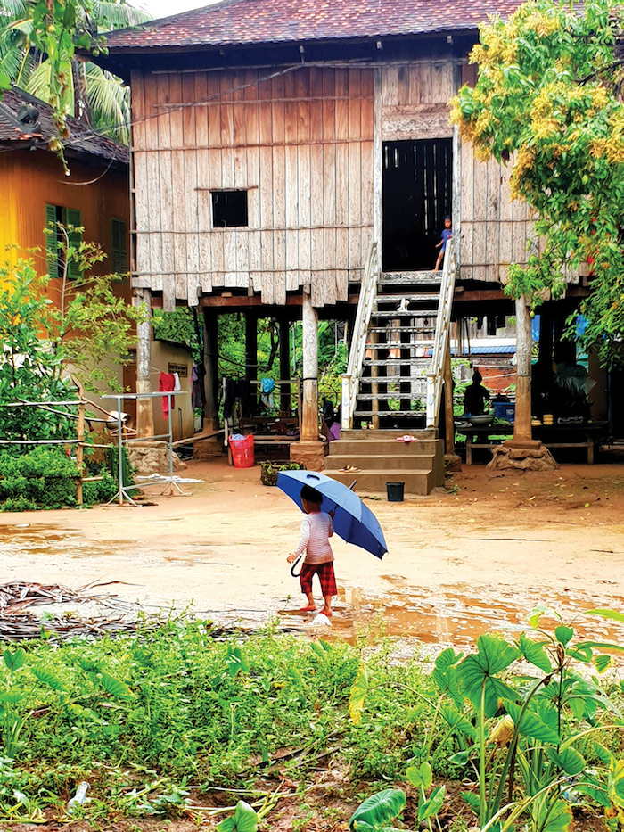 Child dances in the rain in Angkor Bon, a remote Cambodian village in Kampong Chhang province - Mekong River cruise