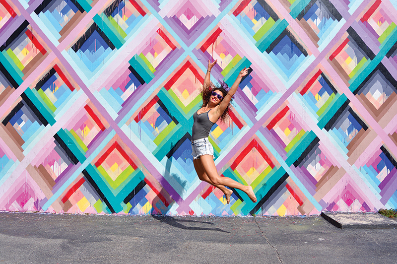 A young woman jumps in front of a street art mural in Miami's Wynwood Walls.