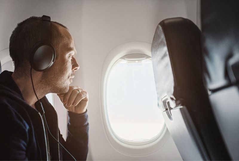 Image of a man on a plane with noise cancelling headphones on