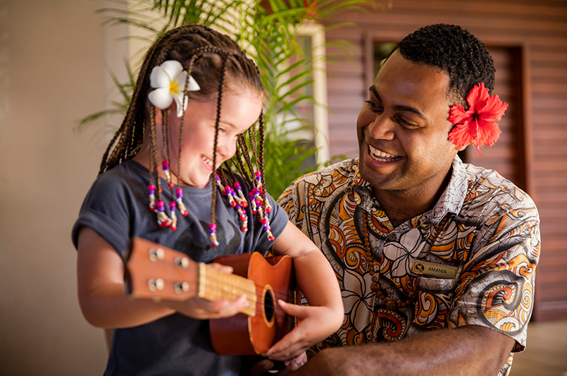 A hotel staff member and young guest at Outrigger Fiji Beach Resort