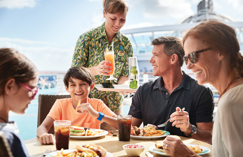 A family sitting around a table having lunch on board. They are wearing the medallions on their wrists