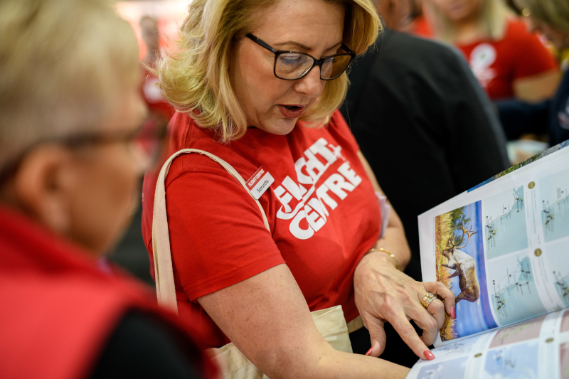 Woman with bright red shirt on looking down at a magazine planning
