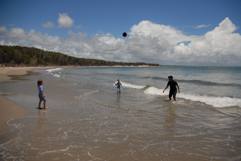 family playing frisbee on beach at iluka, new south wales