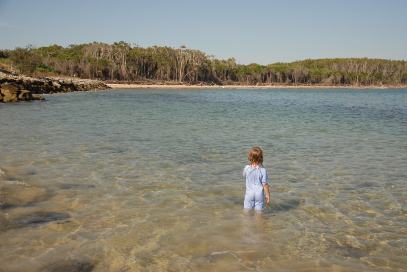 young girl at beach looking out to bushland in Iluka new south wales