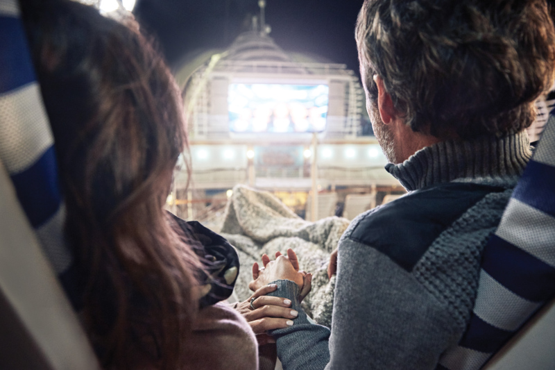 A couple enjoy a movie on the deck of a Princess cruise ship.