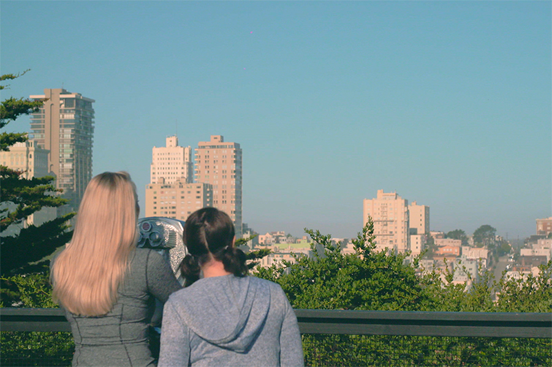Two women look at the viewfinder view from Telegraph Hill in San Francisco.