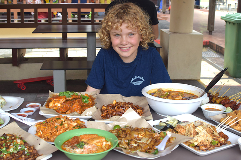 Boy with food from Singapore's hawker centres on table