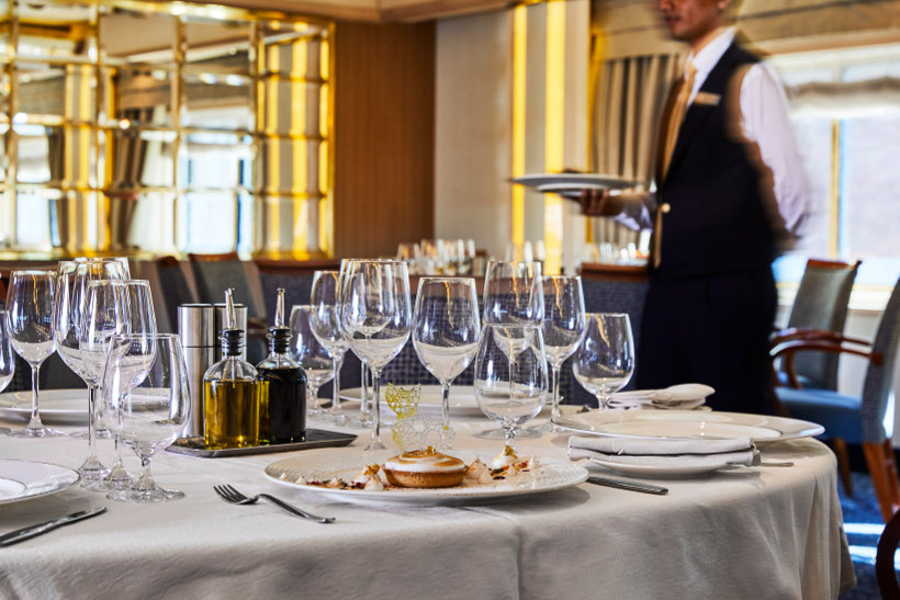 dining setting with waiter behind onboard silver cloud