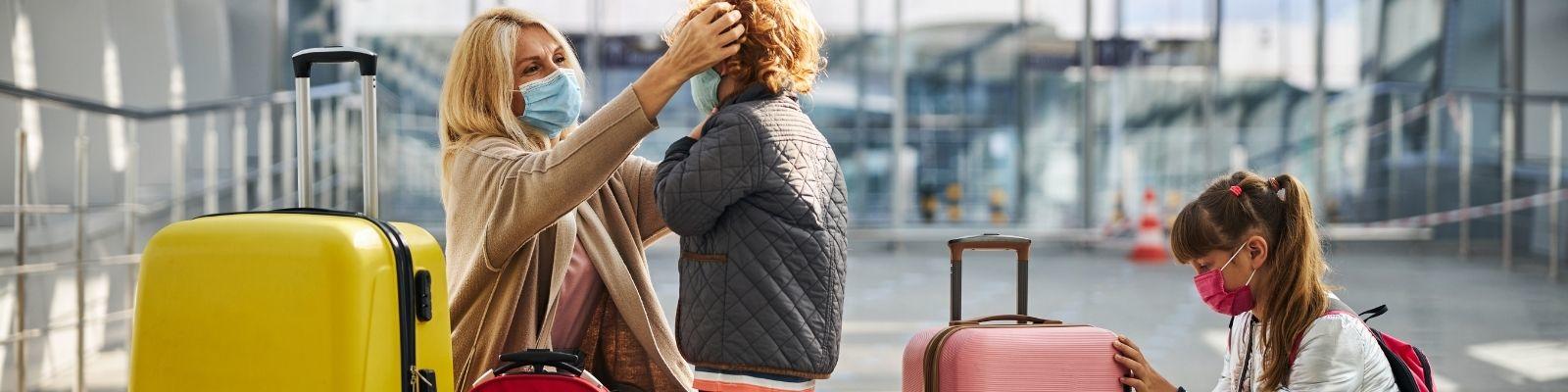 Mother adjusting child's face mask in an airport
