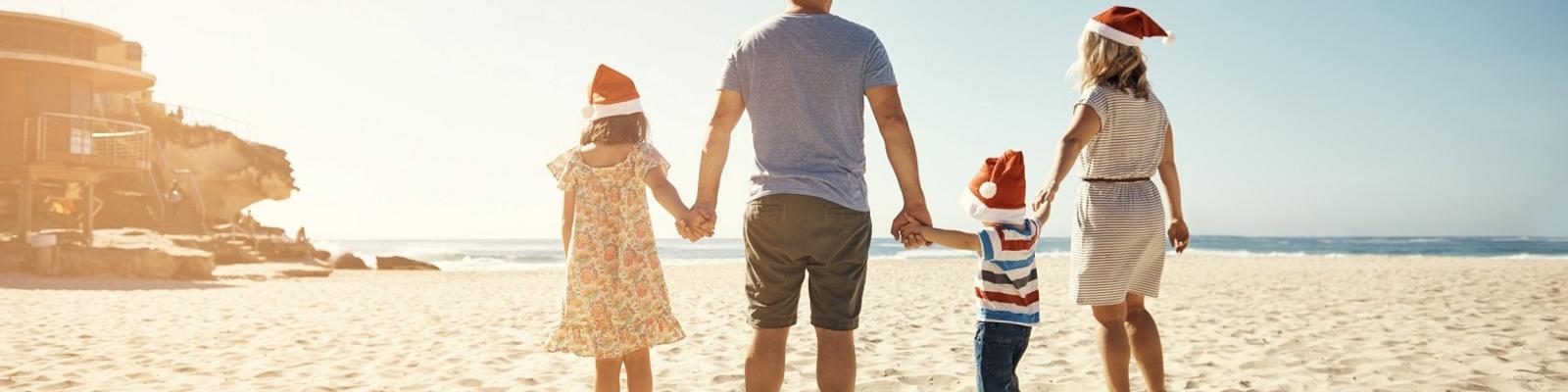 Shot of a family of four walking on the beach on Christmas. Photo: Getty Images.