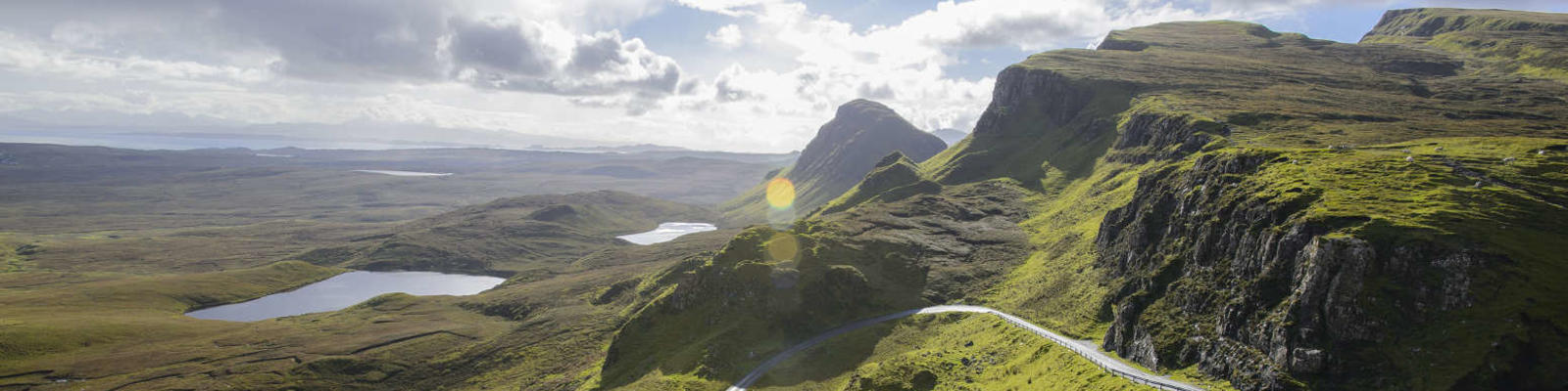 road winding down the side of bare scottish mountain with valley 