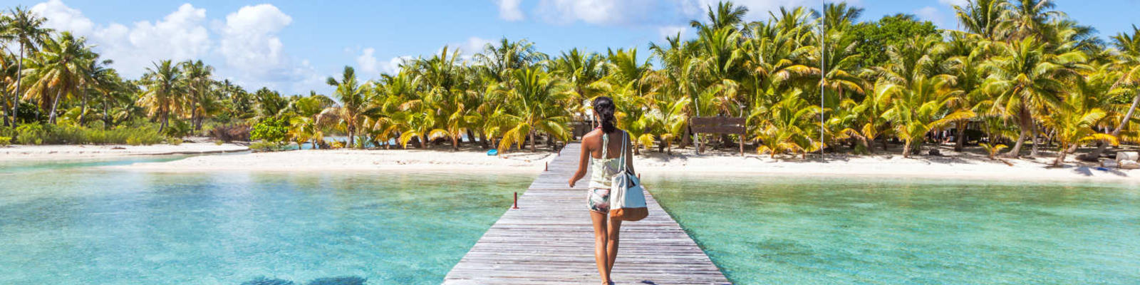woman walking on boardwalk to tropical island