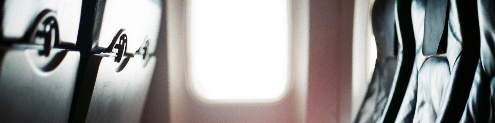 A row of seats on an airplane with sunlight coming in from the window