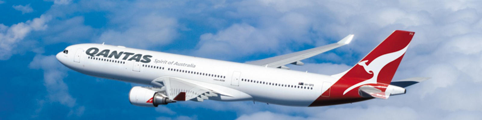 A Qantas A330 flying through the blue skies with fluffy white clouds in the background