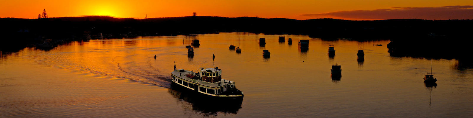 Boats at Port Stephens against an orange sky.