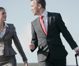 A professionaly dressed man and woman walking together off the tarmac