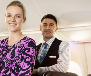 Three Air New Zealand flight attendants inside an aircraft.