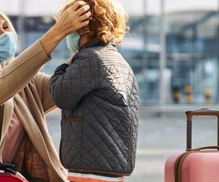 Mother adjusting child's face mask in an airport