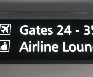 A sign in the airport pointing to gates and lounges